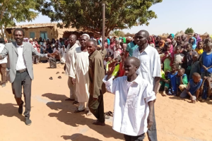 a sudanese child surrounded by a crowd expressing joy and happiness